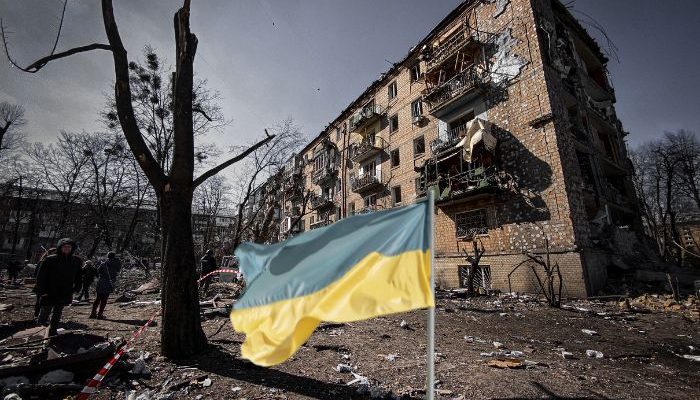 Bandeira da UcrÃ¢nia em frente a um prÃ©dio residencial destruÃ­do pela guerra da RÃºssia...